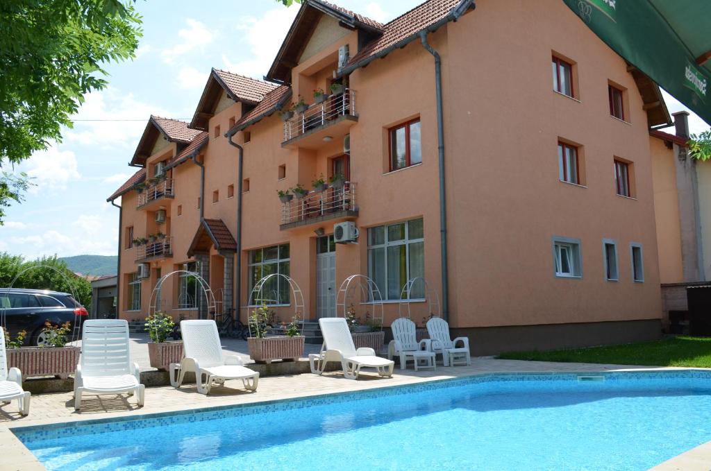 een hotel met een zwembad en stoelen en een gebouw bij VILLA HIPODROM ilidza apartments in Sarajevo