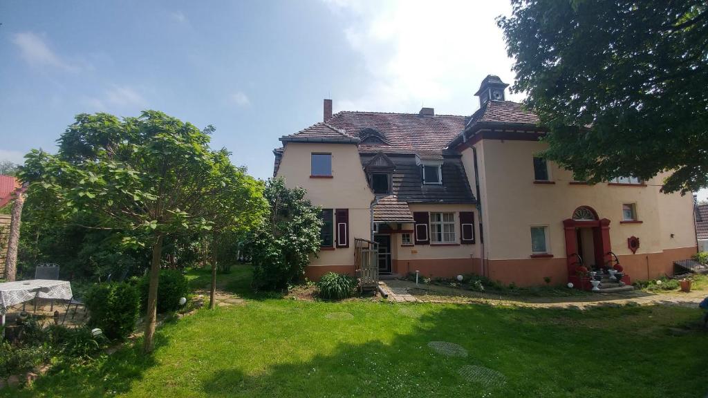 ein großes Haus mit einem Hof mit einem Baum in der Unterkunft Historische Schule "Ferienwohnung Pauline" I&II in Stöbnitz