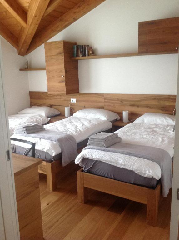 3 Betten in einem Zimmer mit Holzböden in der Unterkunft Rooms dei Minatori in Pergine Valsugana