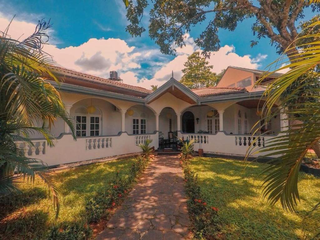 a white house with a palm tree in front of it at The Mango in Kandy