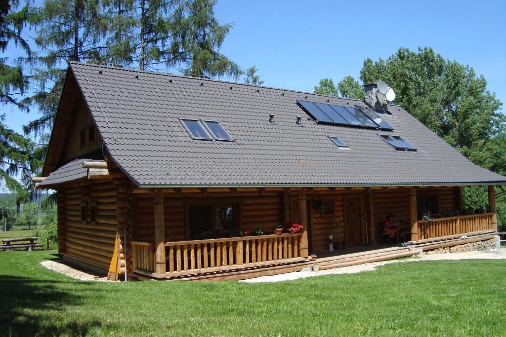 una baita di tronchi con tetto a dondolo e veranda di Penzion-Ranc u Trapera a Hrabušice