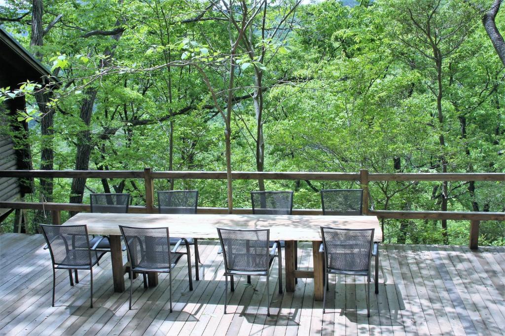 a wooden table and chairs on a deck with trees at Shomarutoge Garden House in Hanno