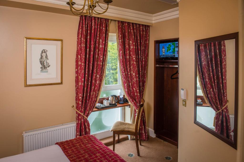 a bedroom with a window with red curtains at Gabriel House Guesthouse in Cork