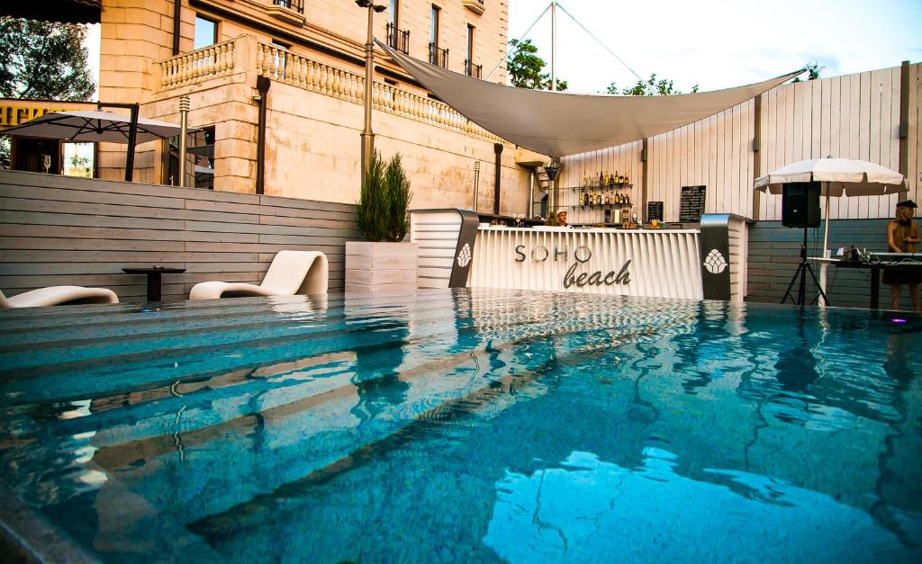 a swimming pool with chairs and an umbrella at Soho Grand Hotel in Azov