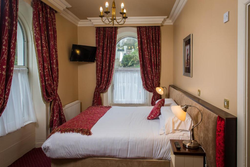 a bedroom with a large bed with red curtains at Gabriel House Guesthouse in Cork