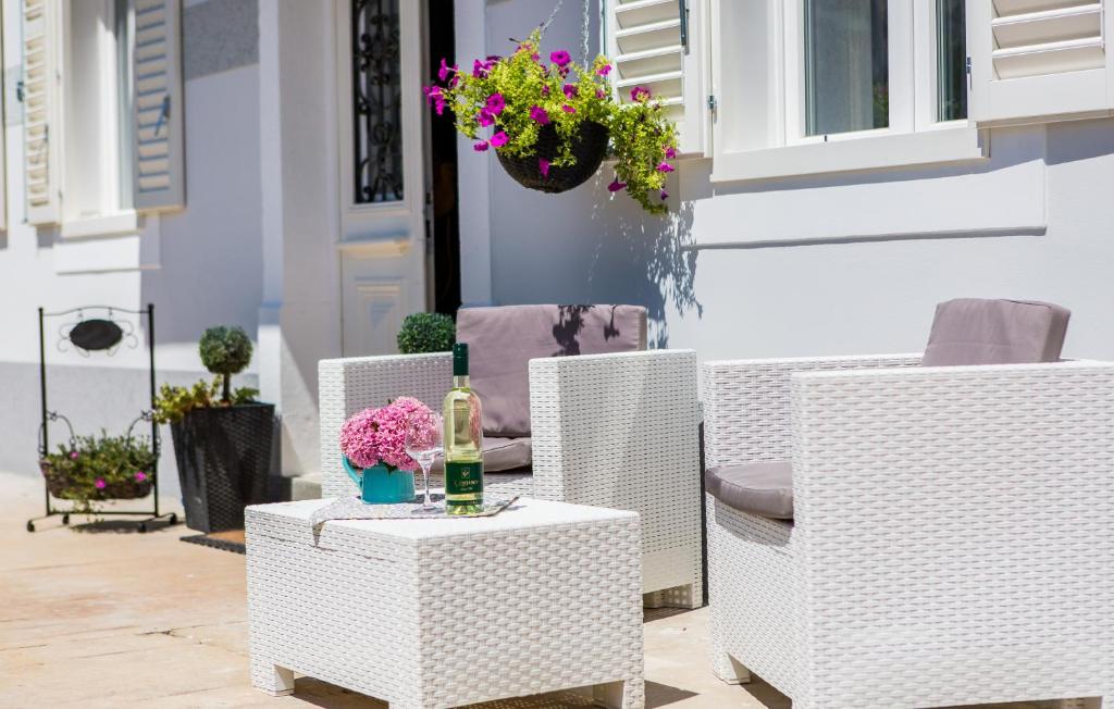 a group of wicker chairs and a bottle of wine on a table at Studio Villa Ivka in Baška