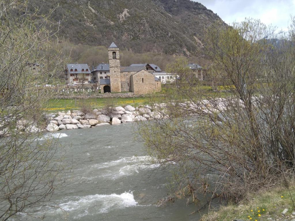 an old building next to a river with a church at Casa Rural Hortal in Barruera