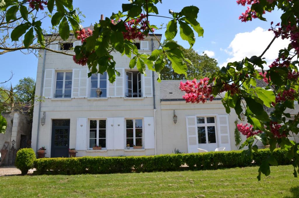 een groot wit huis met roze bloemen bij Le Clos Mademoiselle in Loches
