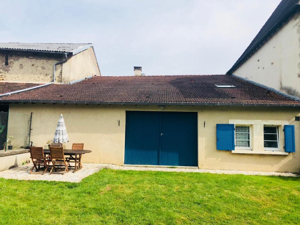 a house with a blue door and a table and chairs at Gîte de la Grande Fontaine in Isches