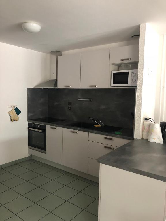 a kitchen with white cabinets and a black counter top at Gîte de la Grande Fontaine in Isches