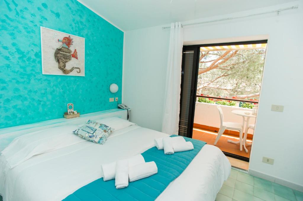 a bedroom with a bed with a blue wall at Hotel Punto Verde in Marina di Campo