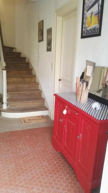 a red cabinet in a room with a staircase at Résidence de Vaux in Nans-sous-Sainte-Anne