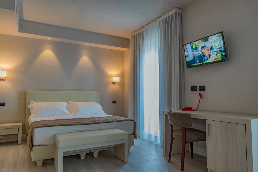 um quarto com uma cama, uma secretária e uma televisão em Hotel Villa Barsanti em Marina di Pietrasanta