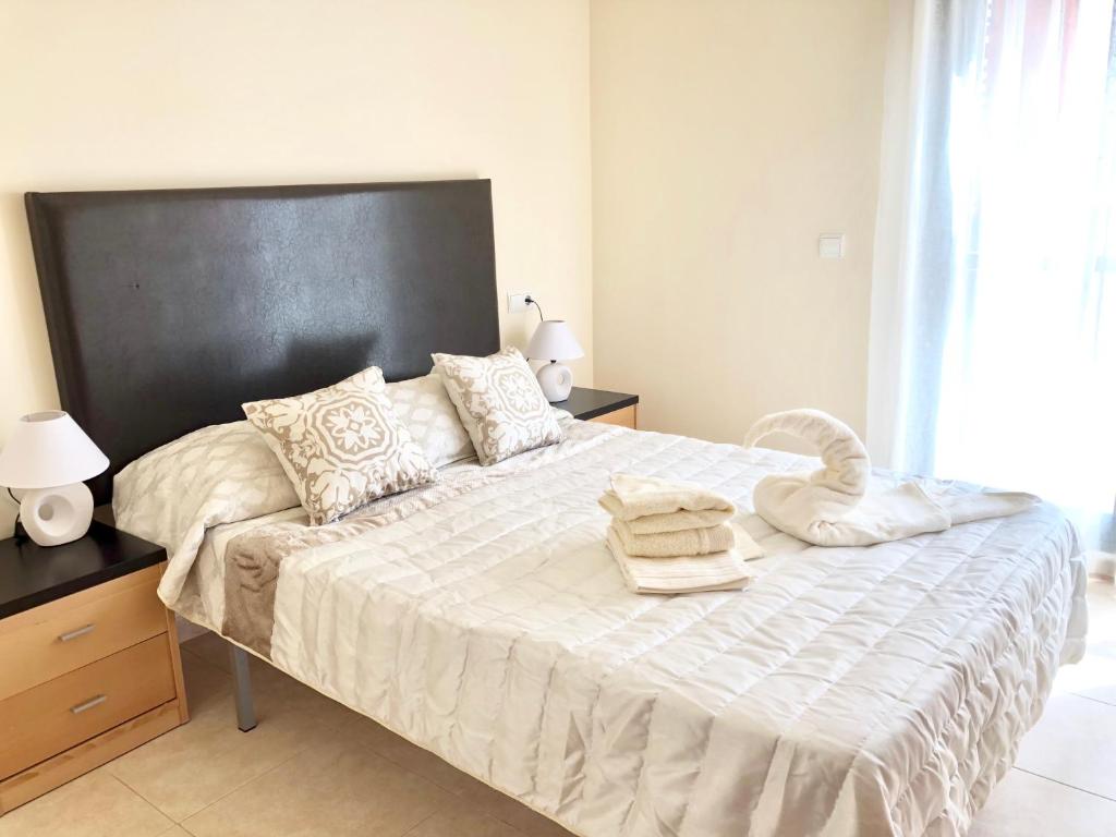 a bedroom with a large white bed with a black headboard at Ático con vistas en Vera Playa in Vera