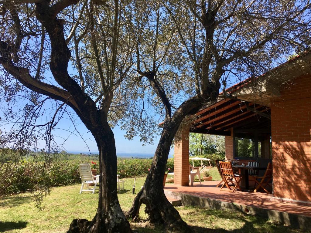 une maison avec une table, des chaises et un arbre dans l'établissement Cottage Gaia with sea view, fenced garden by ToscanaTour, à Guardistallo