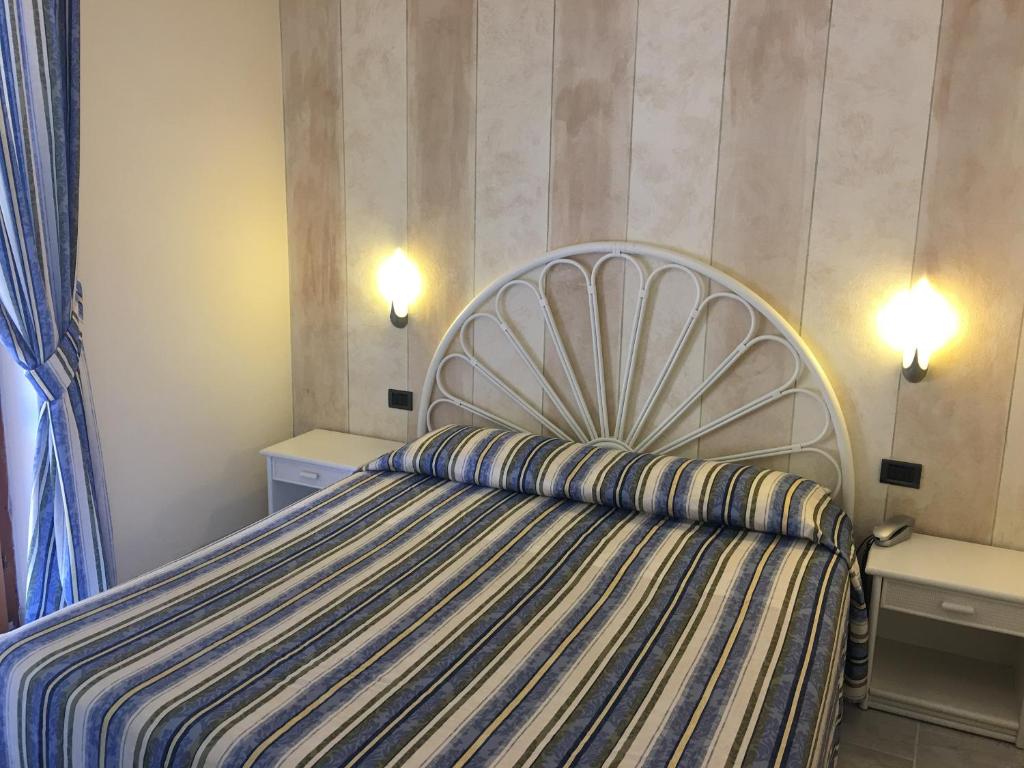 a bedroom with a bed with a striped bedspread at Hotel Danila in Portoferraio
