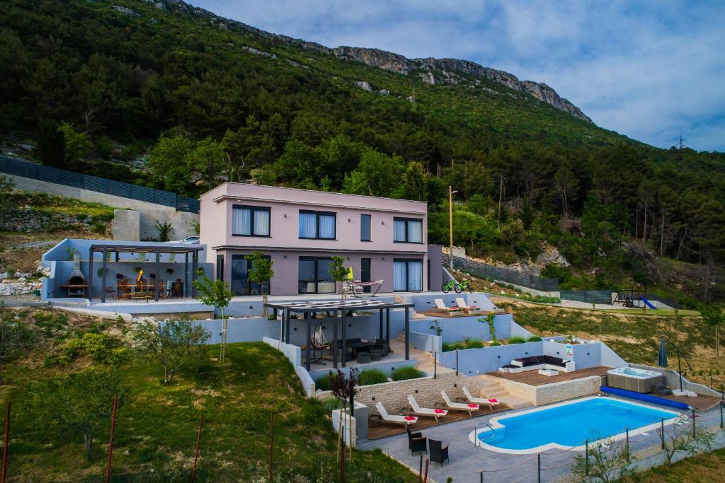 uma casa com piscina em frente a uma montanha em Villa Blue Hill em Kaštela