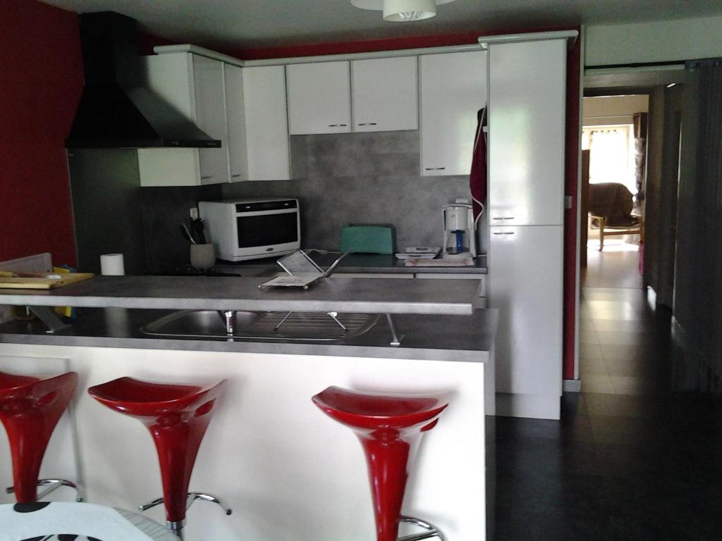 a kitchen with red stools in front of a counter at Gite De LA BALLADE in François