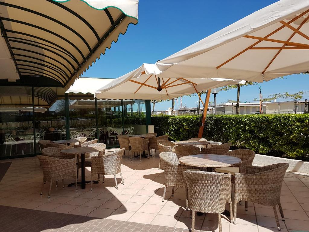 an outdoor patio with tables and chairs and umbrellas at Abahotel in Milano Marittima