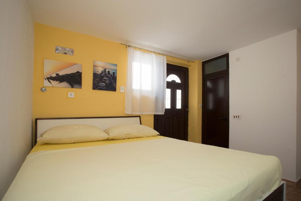 a bedroom with a large white bed with yellow walls at Room Dioklecijan in Split
