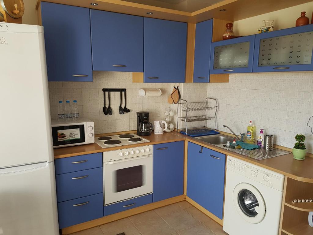 a kitchen with blue cabinets and a white appliance at Mommy's House in Varna City
