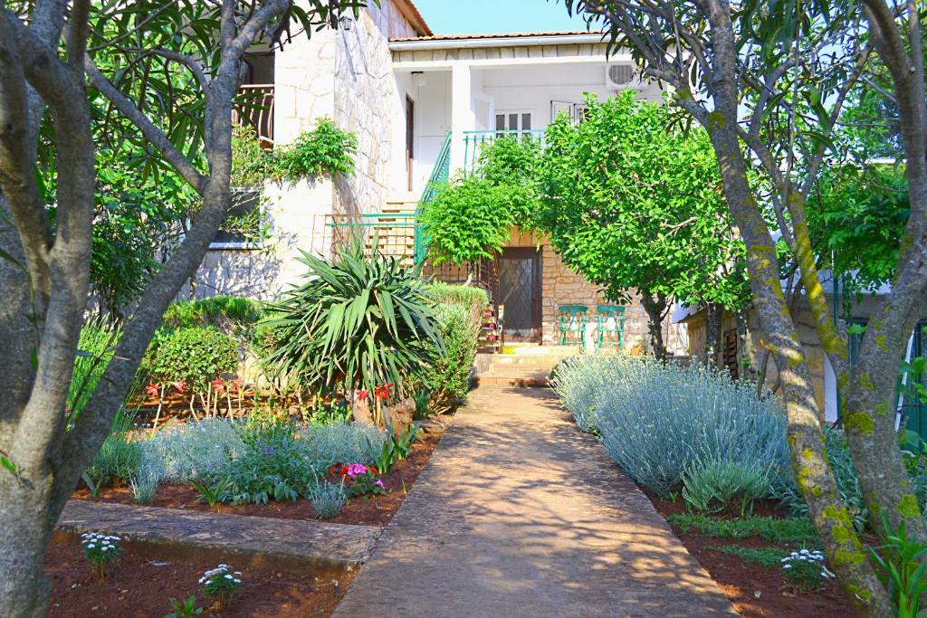 Vrbanj的住宿－Apartments Basina，一座种植了蓝色花卉和树木的花园以及一座建筑
