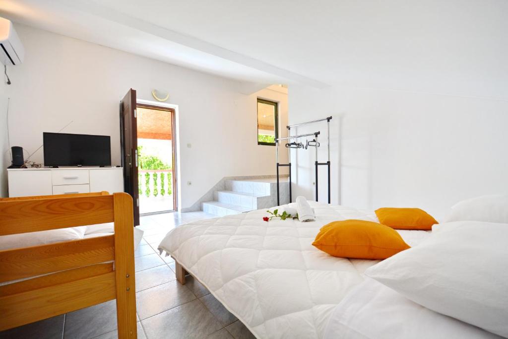 una camera bianca con un grande letto con cuscini gialli di Apartmani Maća a Sikovo