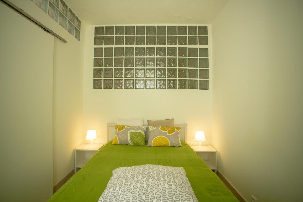 a bedroom with a green bed with two lamps at Apartamento Troino in Setúbal