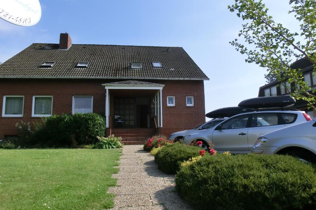une maison avec deux voitures garées devant elle dans l'établissement Haus Strandgut/2, à Duhnen