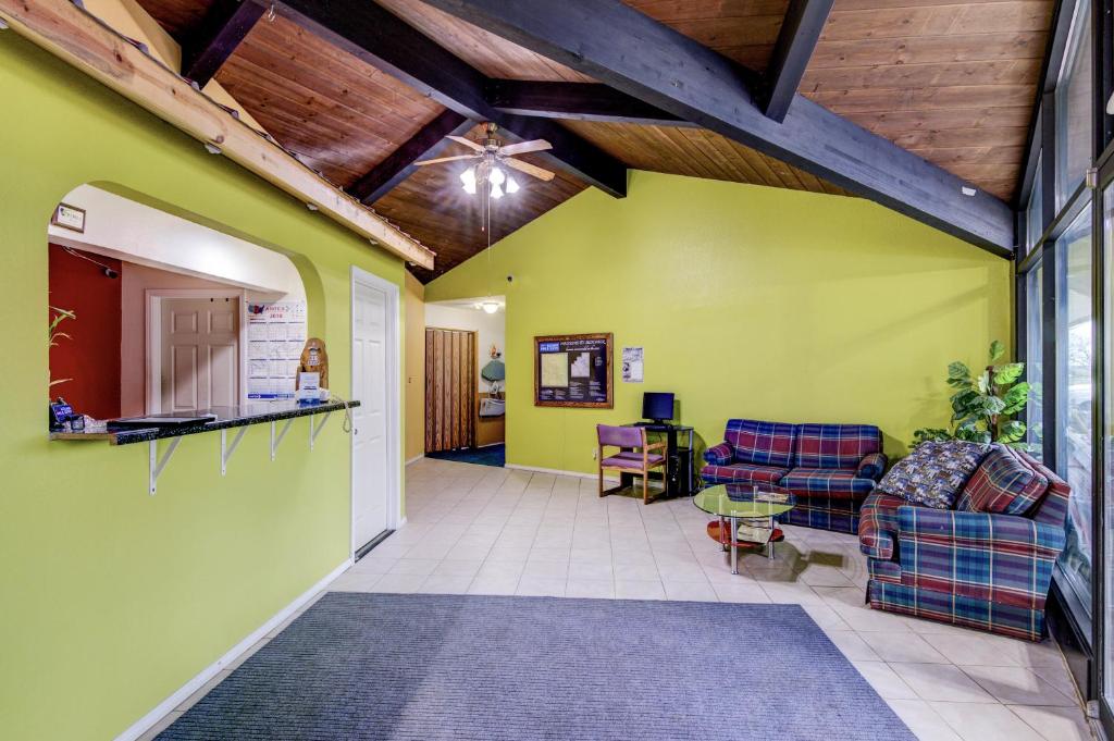 a living room with green walls and a wooden ceiling at Bloomer Inn & Suites in Bloomer
