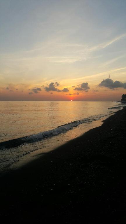 a sunset on a beach with the ocean at Solaluna Beach Homestay in Amed