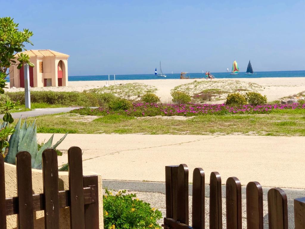 una valla de madera frente a una playa en Barcaresa-MAISONNETTE VUE MER PIEDS DANS L'EAU WIFI, en Port Leucate