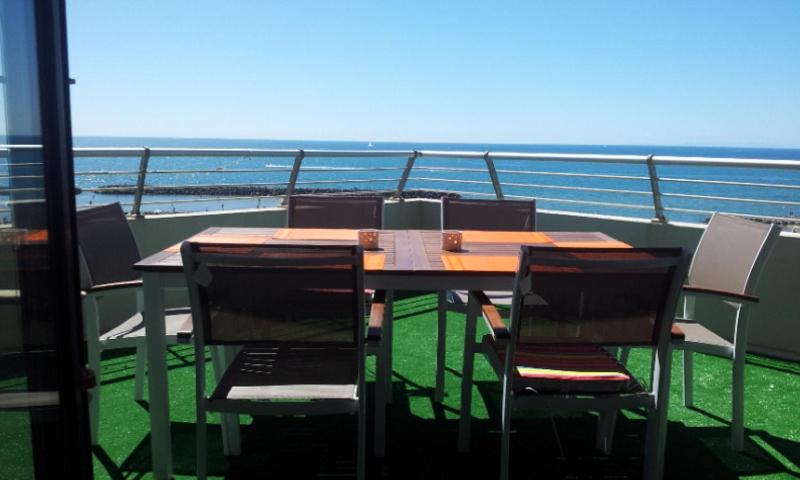 une table et des chaises sur un balcon avec l'océan dans l'établissement appartement 58 m 2 en 1 ere ligne ,vue mer panoramique ,2 terrasses dont une couverte résidence le Sunset, au Cap d'Agde