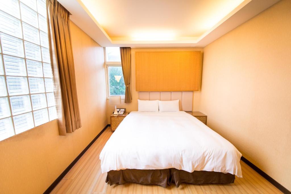 礁溪鄉的住宿－青池人文溫泉旅館，卧室配有白色的床和窗户。