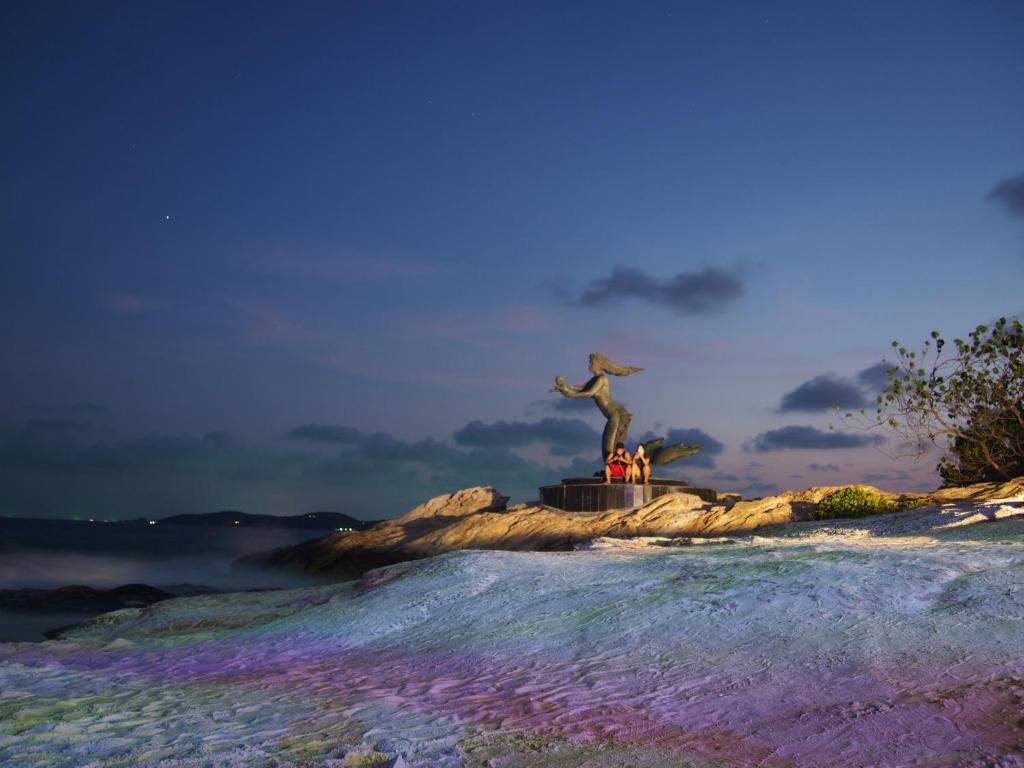 Una estatua de una persona sobre una roca en el agua. en Nong Nuey Rooms, en Ko Samed
