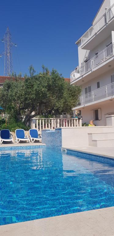 a swimming pool with two lounge chairs and a building at Apartments Antonio in Cavtat