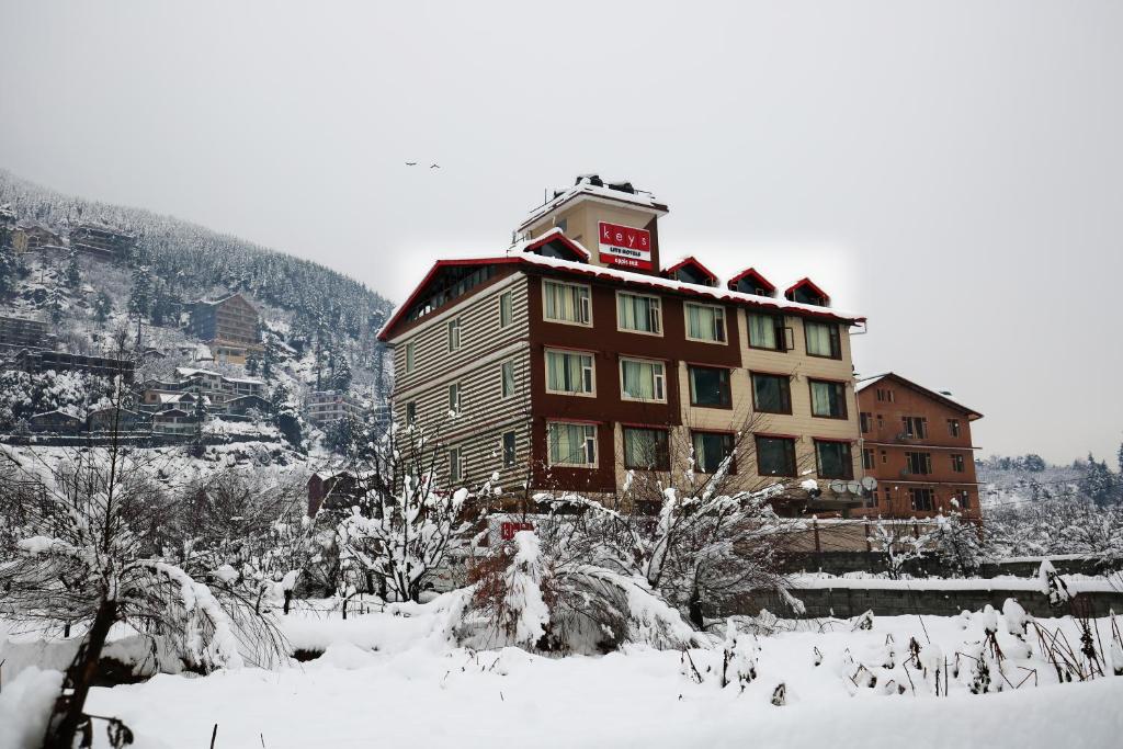 a large building in the snow in front of a mountain at Hotels Apple Nest in Manāli