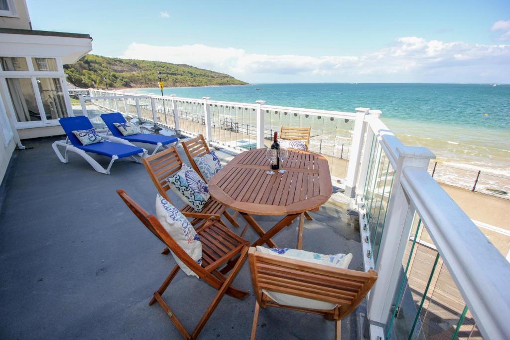 un tavolo e sedie su un balcone con vista sulla spiaggia di Garden Apartment, 2 Pilots Point a Totland