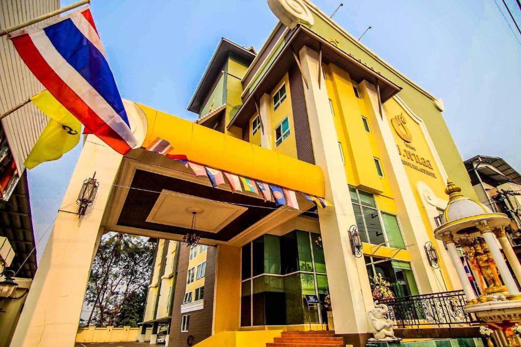 un edificio amarillo con una bandera delante de él en Chour Palace Hotel, en Mae Sai