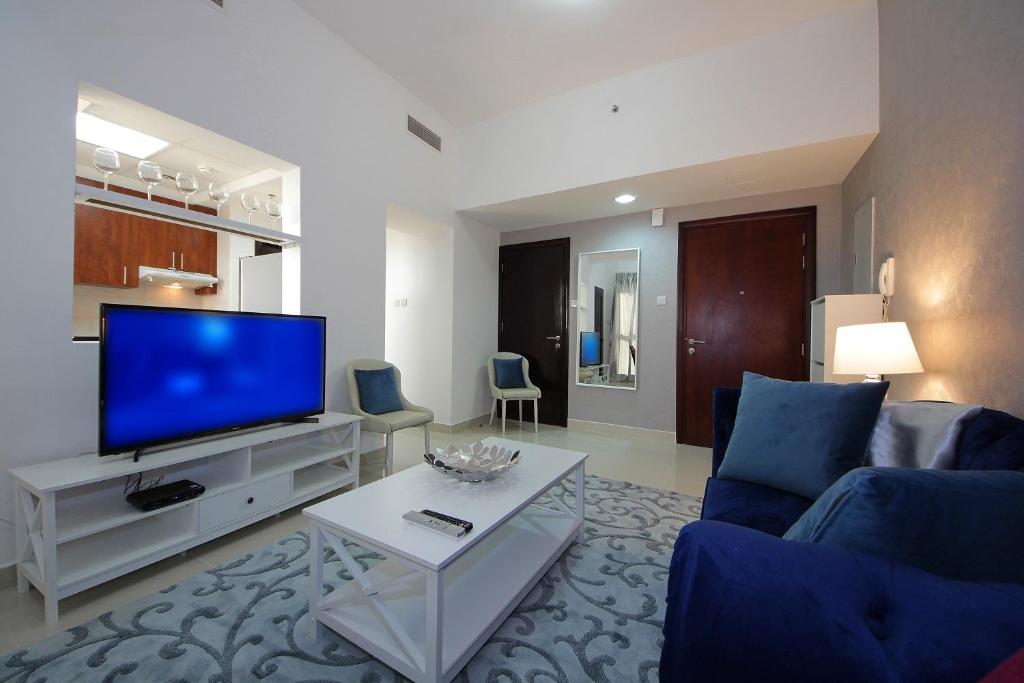 a living room with a blue couch and a tv at New Arabian Holiday Homes - Escan Tower in Dubai