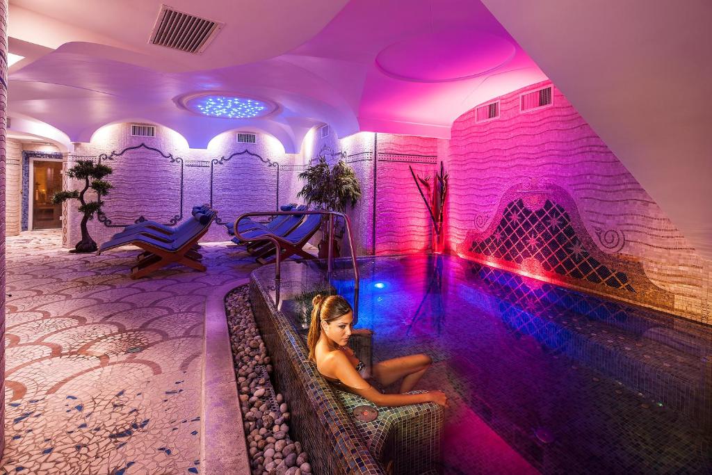 a woman sitting in a hot tub in a room with purple lighting at Sorriso Thermae Resort & Spa in Ischia