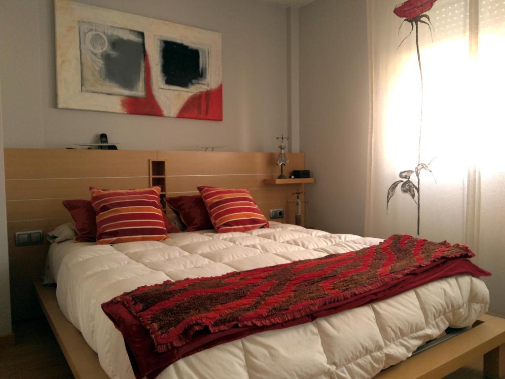 um quarto com uma cama grande e almofadas vermelhas em La casa de Marta em Murchante