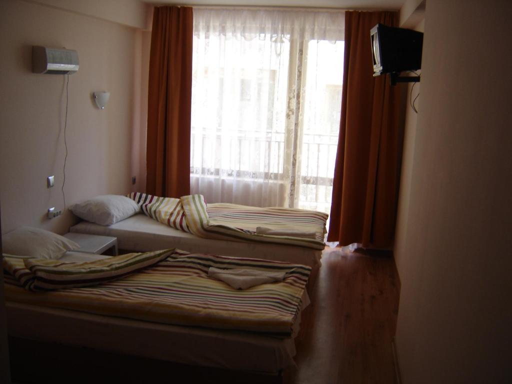 a room with two beds in front of a window at Central Park Family Hotel in Kavarna