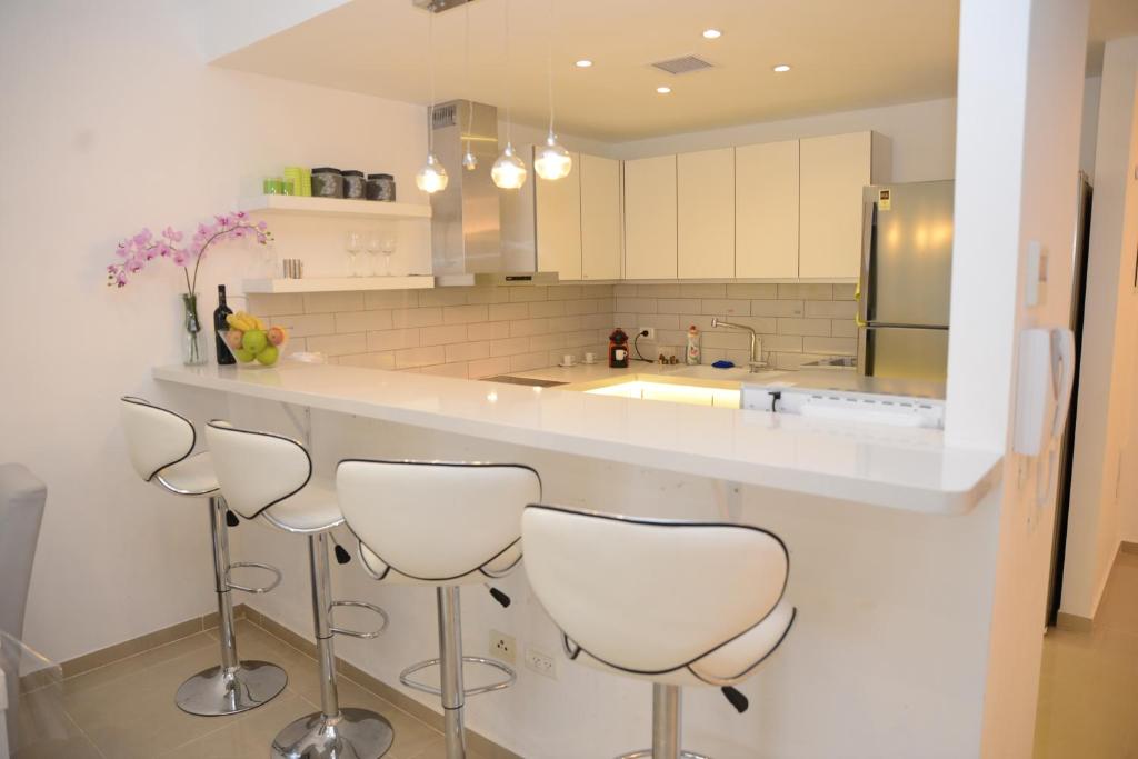 a kitchen with a counter with four stools at Saidoff, amazing 4 br, 3 bath in city center, new building in Jerusalem