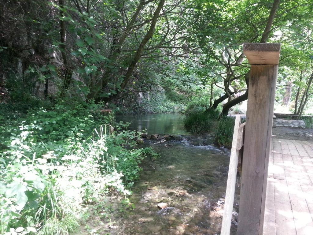 a wooden fence next to a river with trees at Douskas Place in Vouvopótamos
