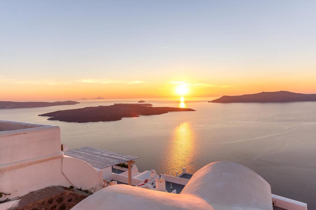 una puesta de sol sobre el océano con las islas en el agua en Sunset Hotel, en Firostefani