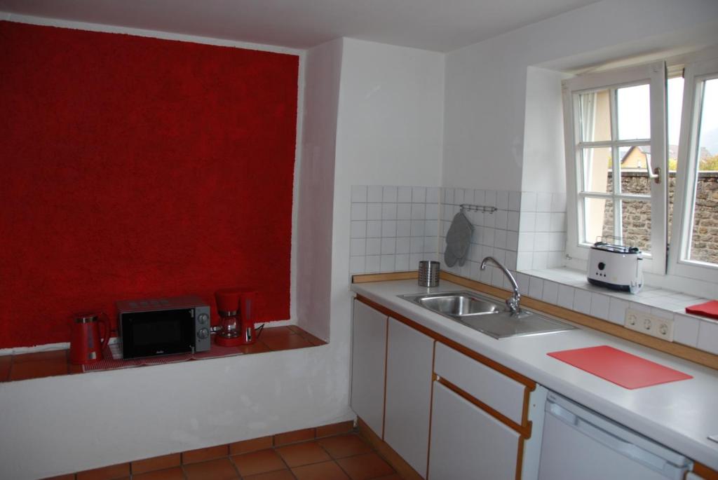 cocina con fregadero y pared roja en Turm Hämelmaous en Echternach