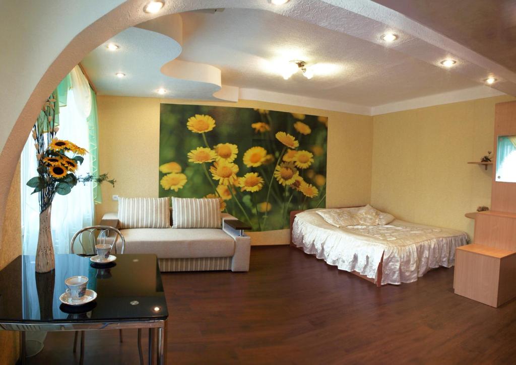 a living room with a bed and a painting of flowers at Квартира на проспекте Александра Поля с ромашками (Apartment on the Oleksandra Polia avenue with chamomiles) in Dnipro