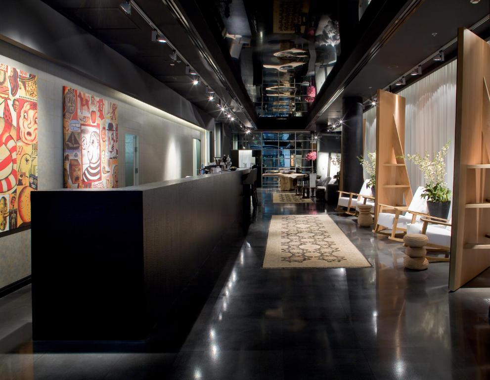 a lobby with a long corridor with chairs and tables at Leonardo Boutique Hotel Tel Aviv in Tel Aviv