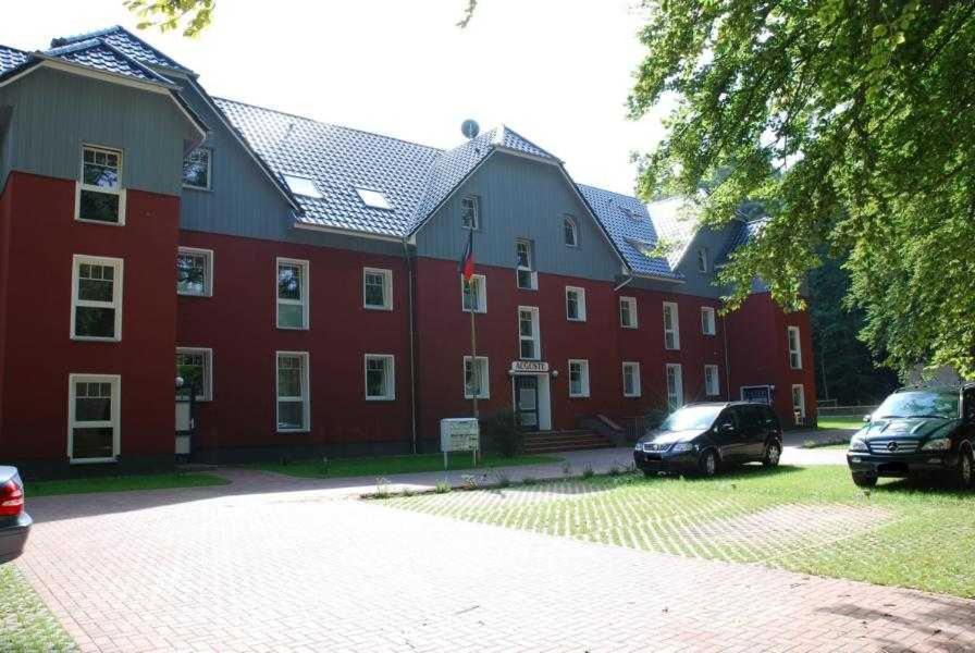 un grand bâtiment rouge avec des voitures garées devant lui dans l'établissement Haus Auguste Appartement 20, à Bansin